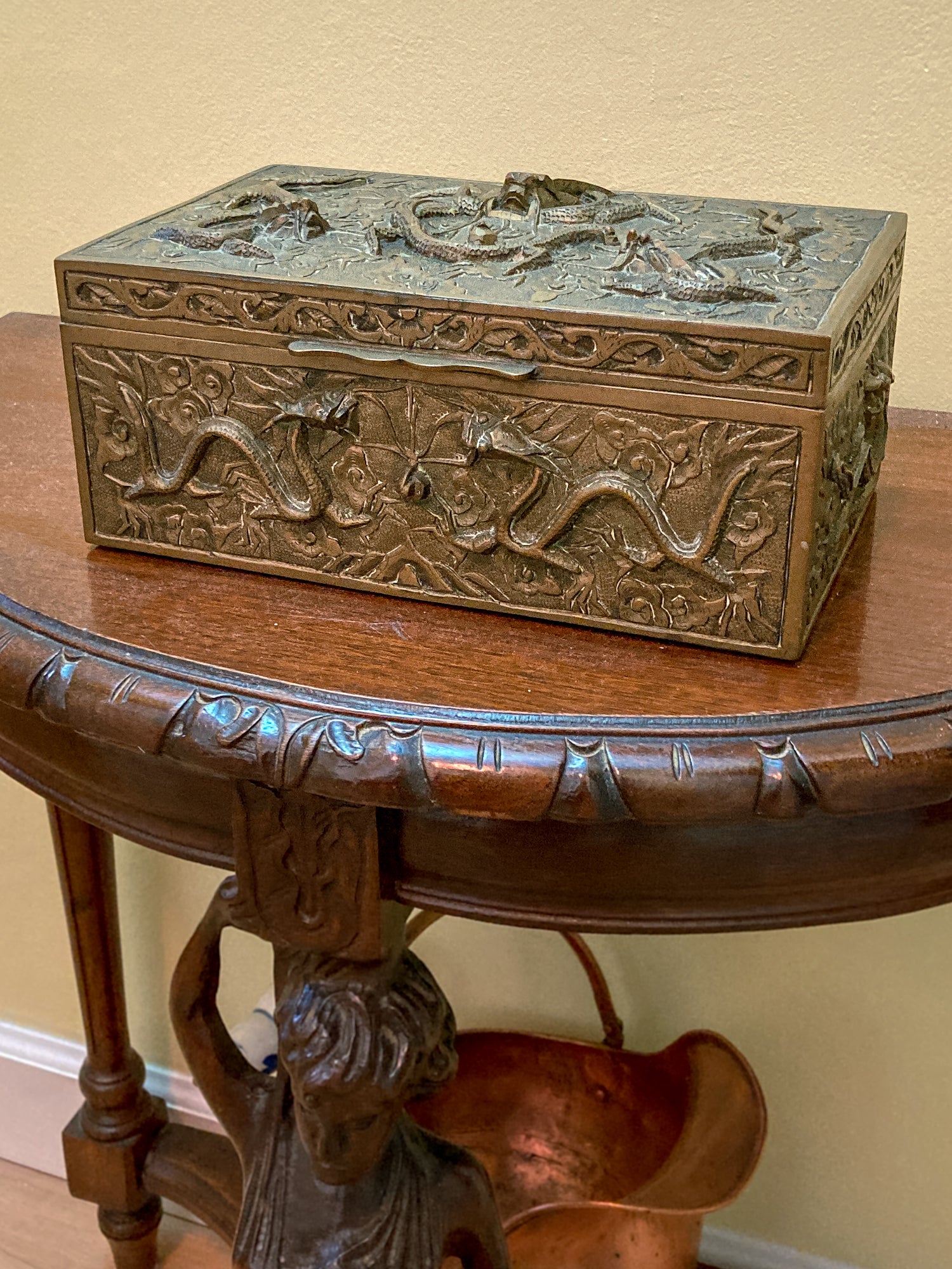 Decorative brass box with intricate designs on a wooden table. Antique Hand Engraved Sculptural Brass Dragon Wood Lined Cigar Box