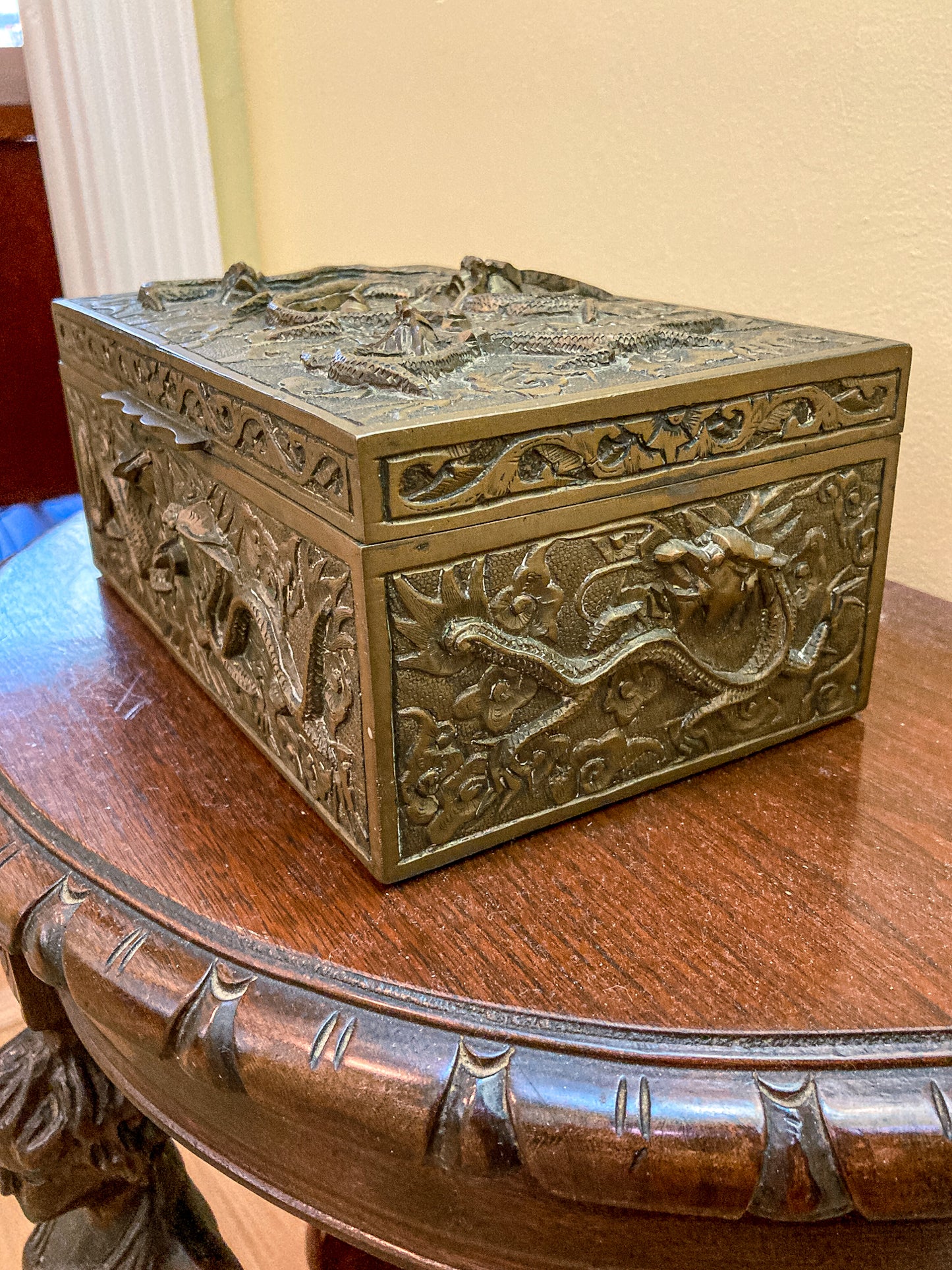 Decorative bronze box with intricate carvings on a wooden surface Antique Hand Engraved Sculptural Brass Dragon Wood Lined Cigar Box