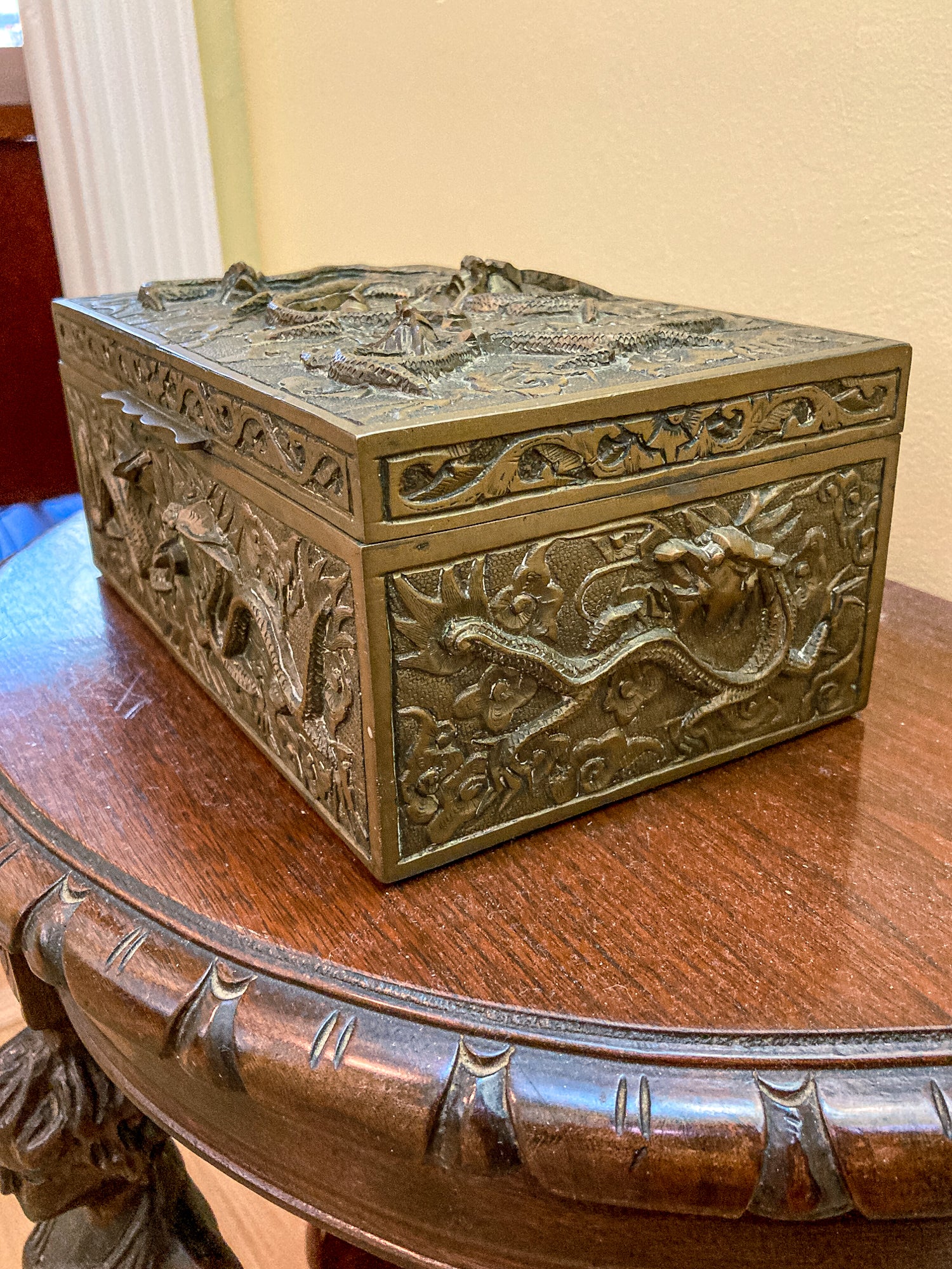 Decorative bronze box with intricate carvings on a wooden surface Antique Hand Engraved Sculptural Brass Dragon Wood Lined Cigar Box