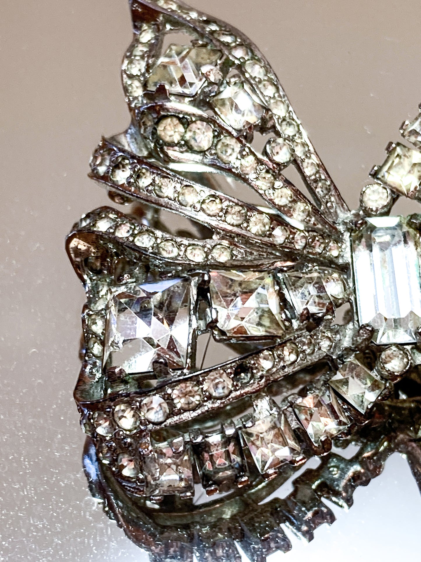 Vintage Coro Sterling Silver Clear Glass Rhinestone Asymmetric Bow Brooch Pin on mirrored white background close up
