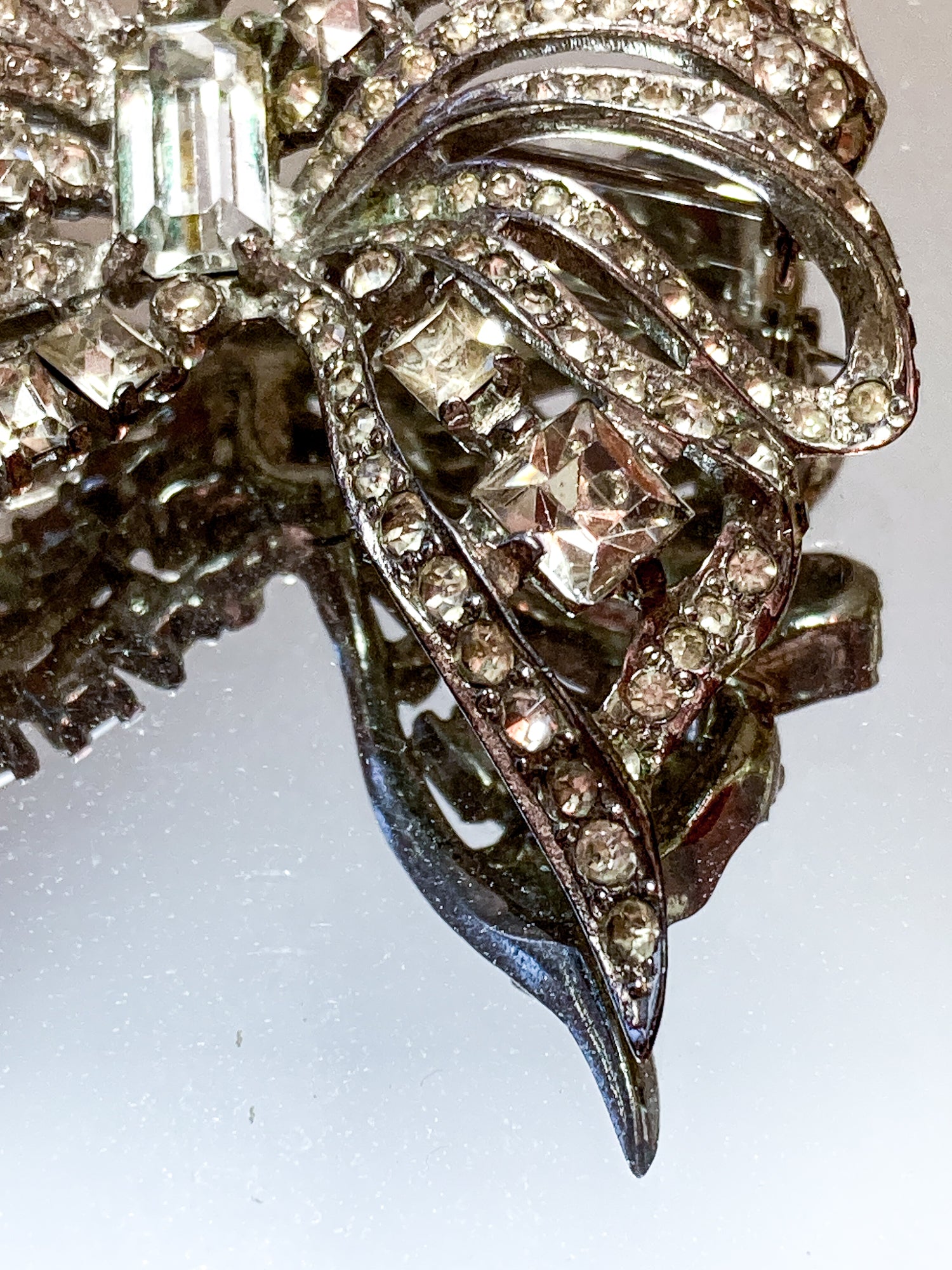 Vintage Coro Sterling Silver Clear Glass Rhinestone Asymmetric Bow Brooch Pin on mirrored white background close up