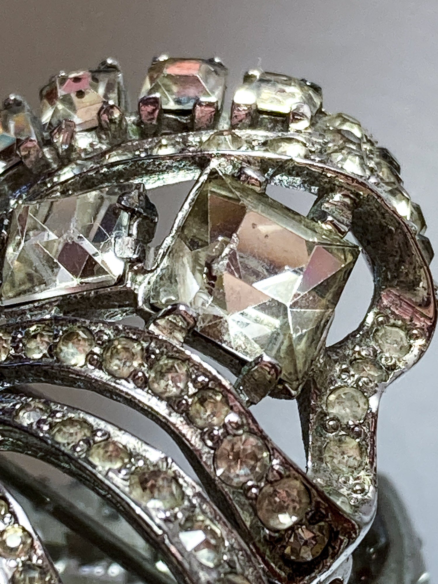 Vintage Coro Sterling Silver Clear Glass Rhinestone Asymmetric Bow Brooch Pin on mirrored white background close up chipped rhinestone
