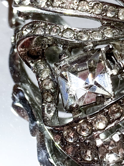 Vintage Coro Sterling Silver Clear Glass Rhinestone Asymmetric Bow Brooch Pin on mirrored white background close up chipped rhinestone