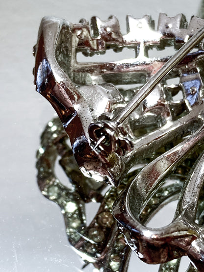 Vintage Coro Sterling Silver Clear Glass Rhinestone Asymmetric Bow Brooch Pin on mirrored white background close up pin