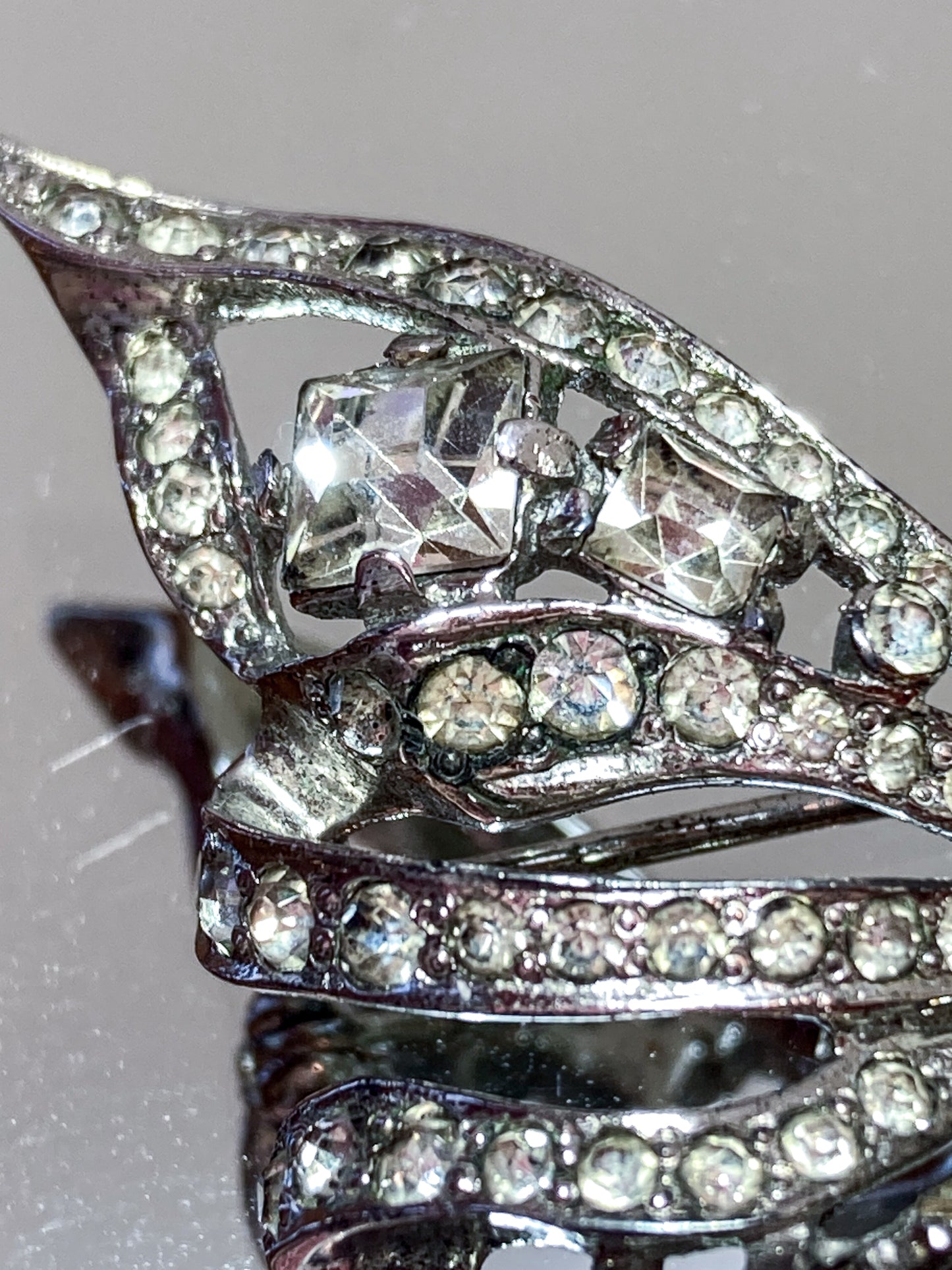 Vintage Coro Sterling Silver Clear Glass Rhinestone Asymmetric Bow Brooch Pin on mirrored white background close up