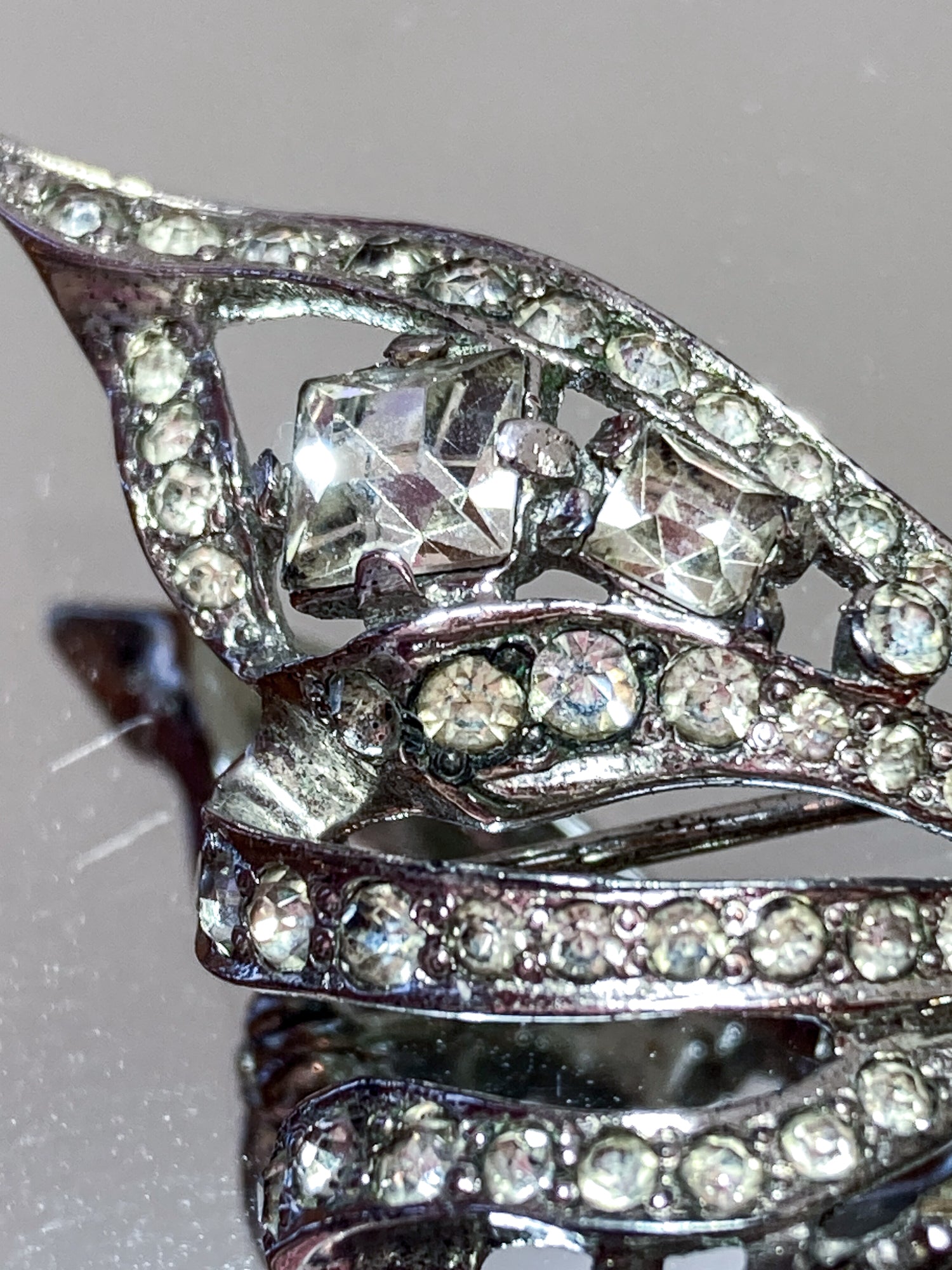 Vintage Coro Sterling Silver Clear Glass Rhinestone Asymmetric Bow Brooch Pin on mirrored white background close up