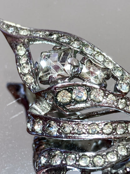 Vintage Coro Sterling Silver Clear Glass Rhinestone Asymmetric Bow Brooch Pin on mirrored white background close up