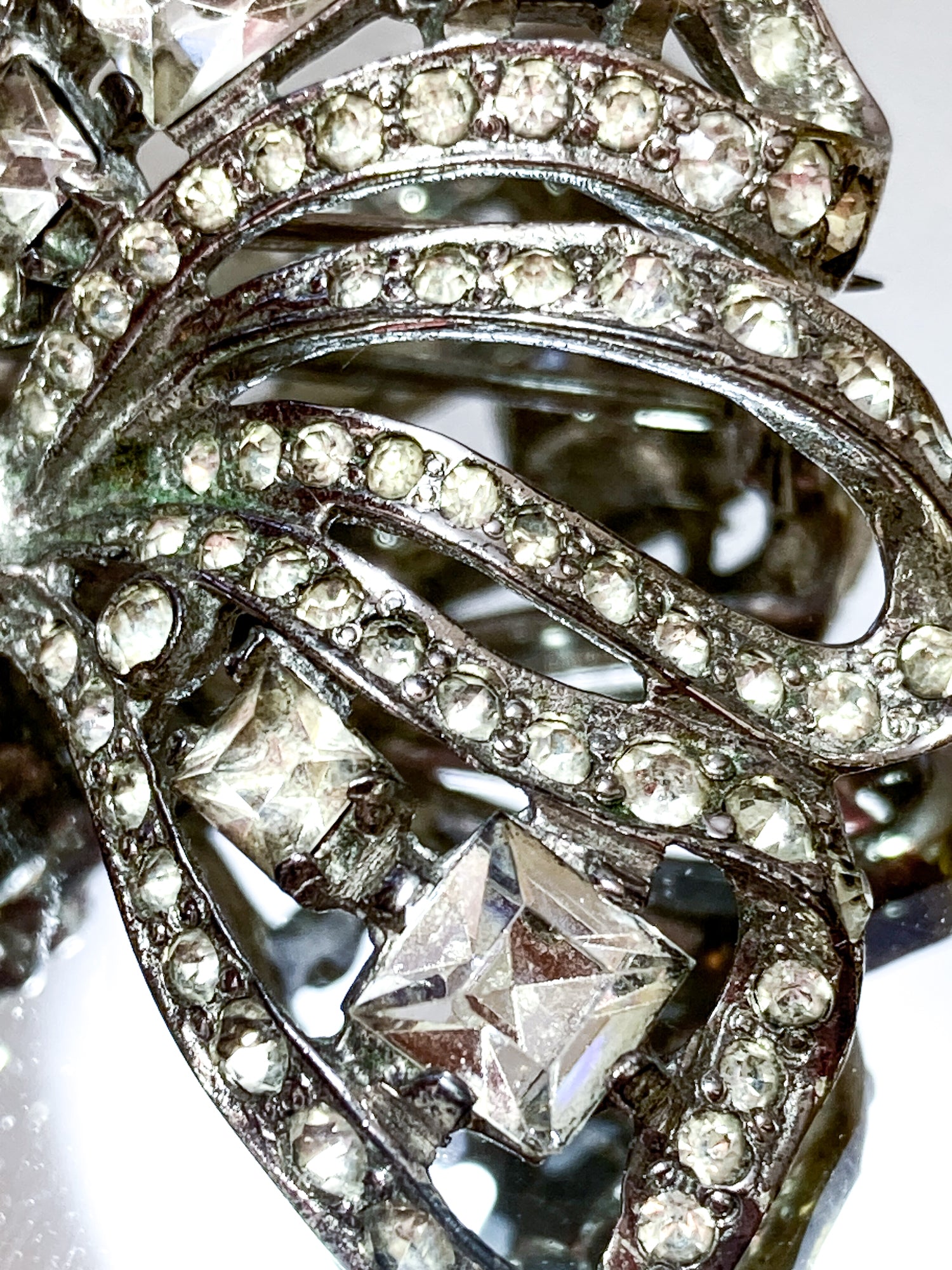 Vintage Coro Sterling Silver Clear Glass Rhinestone Asymmetric Bow Brooch Pin on mirrored white background close up