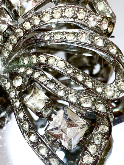 Vintage Coro Sterling Silver Clear Glass Rhinestone Asymmetric Bow Brooch Pin on mirrored white background close up