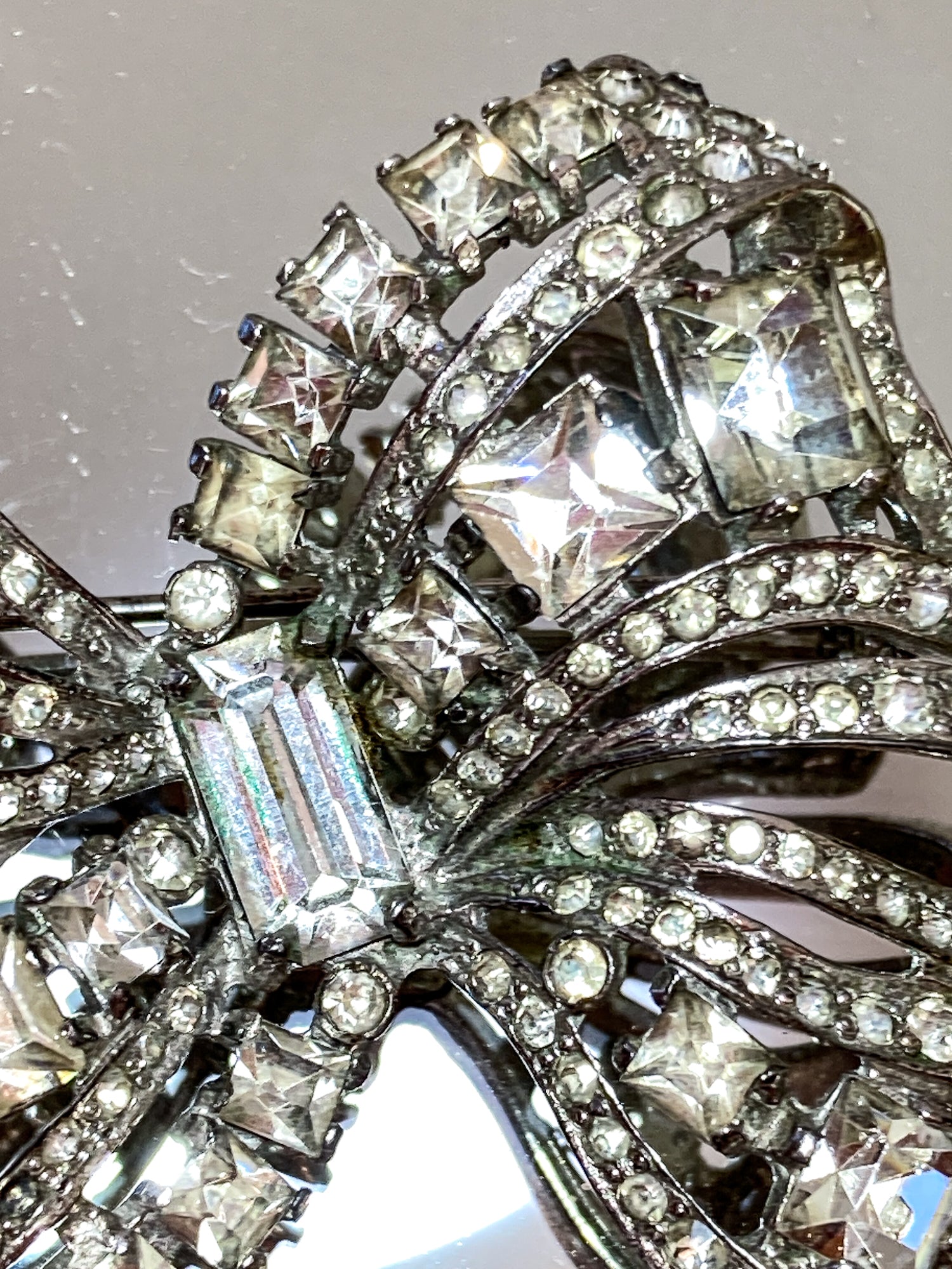 Vintage Coro Sterling Silver Clear Glass Rhinestone Asymmetric Bow Brooch Pin on mirrored white background close up