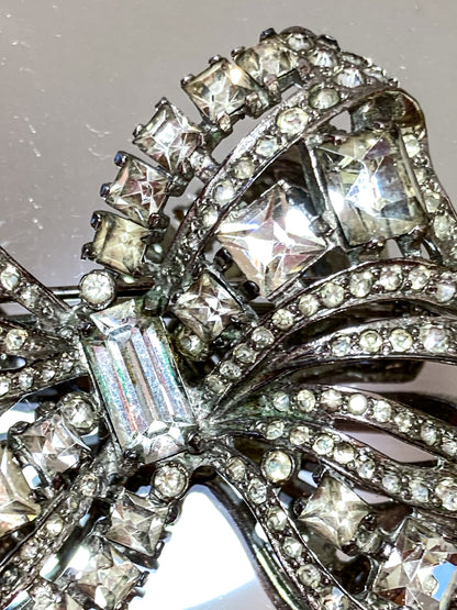 Vintage Coro Sterling Silver Clear Glass Rhinestone Asymmetric Bow Brooch Pin on mirrored white background close up