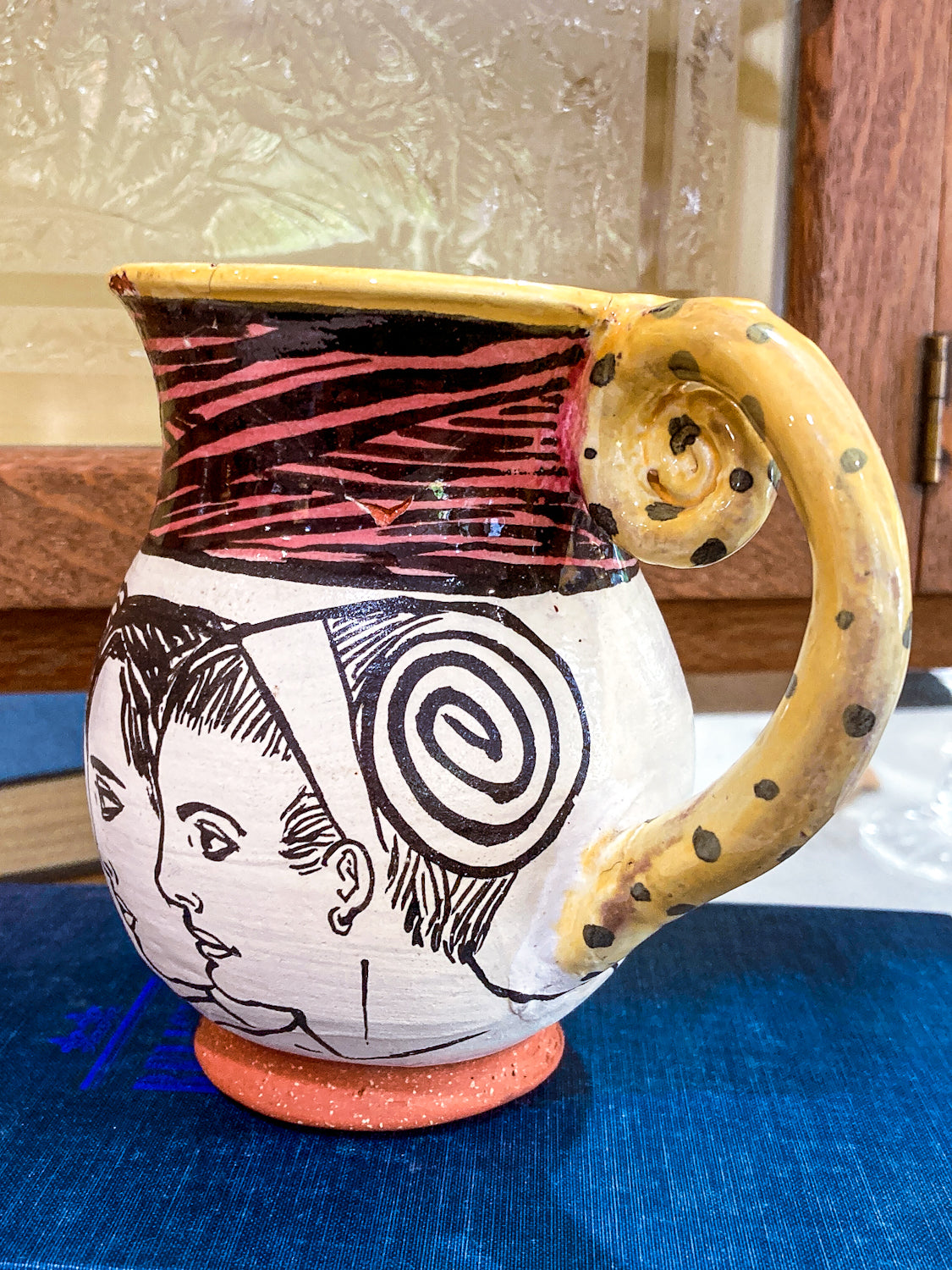 Ceramic pitcher with artistic design on a blue surface Vintage Daniel Postotnik Hand Potted Illustrative Portrait Mug As Found