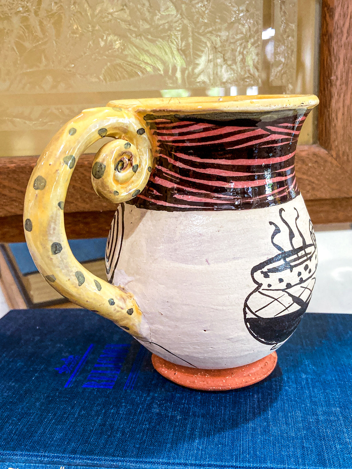 Ceramic mug with a unique handle design on a blue surface Vintage Daniel Postotnik Hand Potted Illustrative Portrait Mug As Found