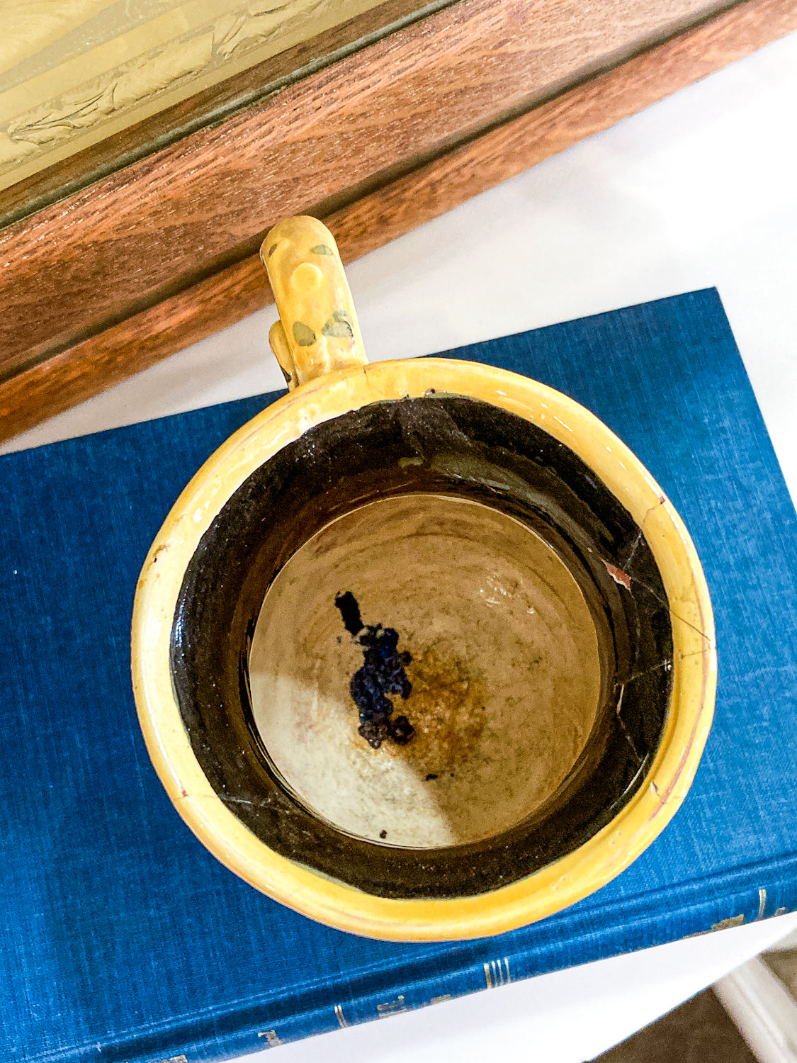 Yellow mug with a handle on a blue book Vintage Daniel Postotnik Hand Potted Illustrative Portrait Mug As Found