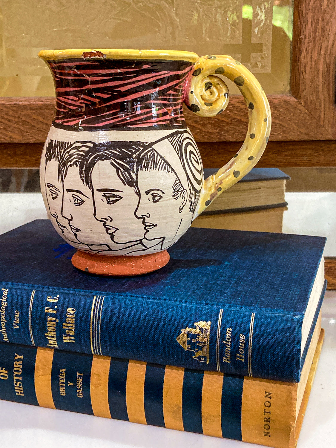 Ceramic mug with artistic handle on top of books Vintage Daniel Postotnik Hand Potted Illustrative Portrait Mug As Found