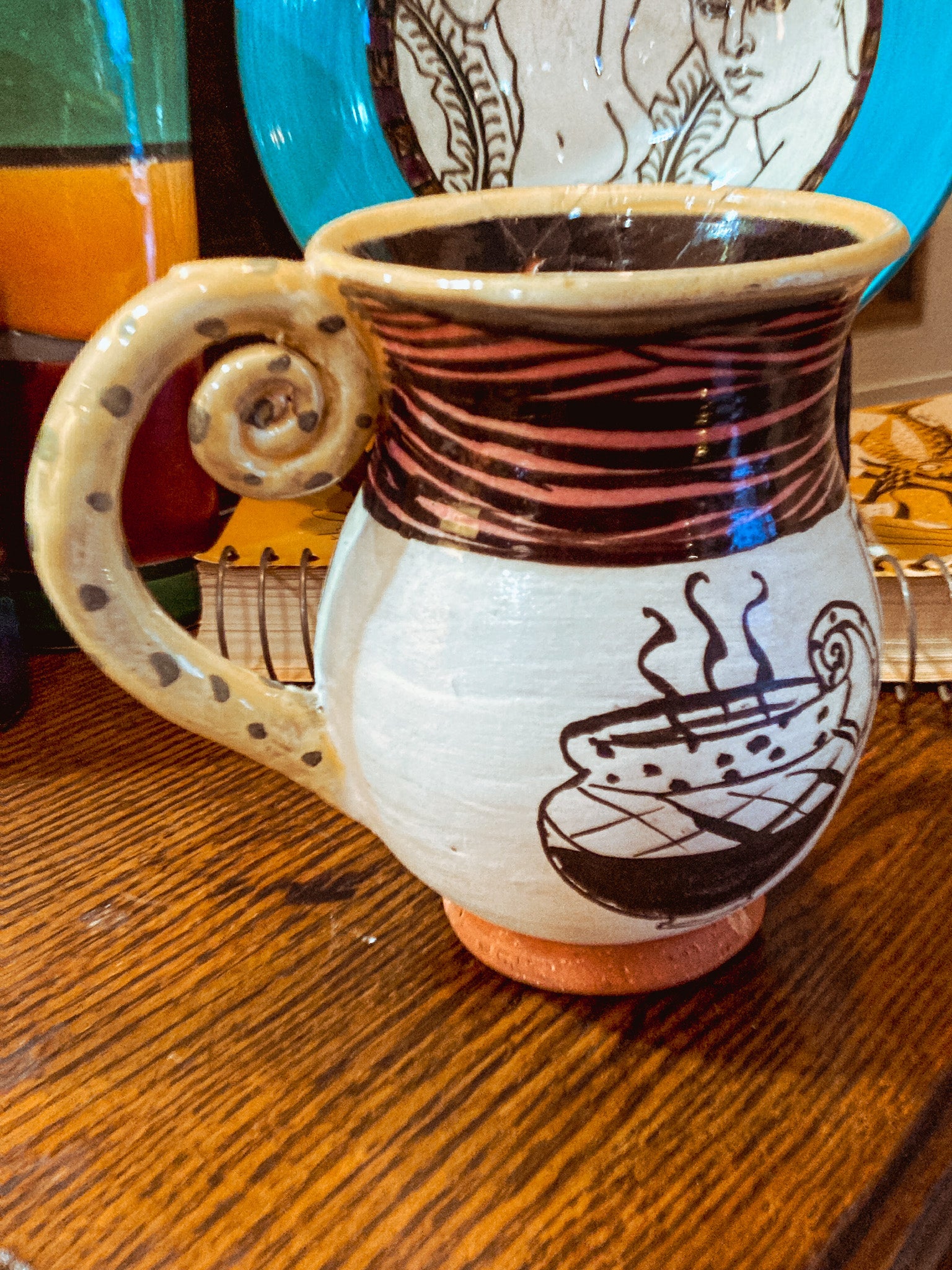 Ceramic mug with decorative handle and design on a wooden surface Vintage Daniel Postotnik Hand Potted Illustrative Portrait Mug As Found