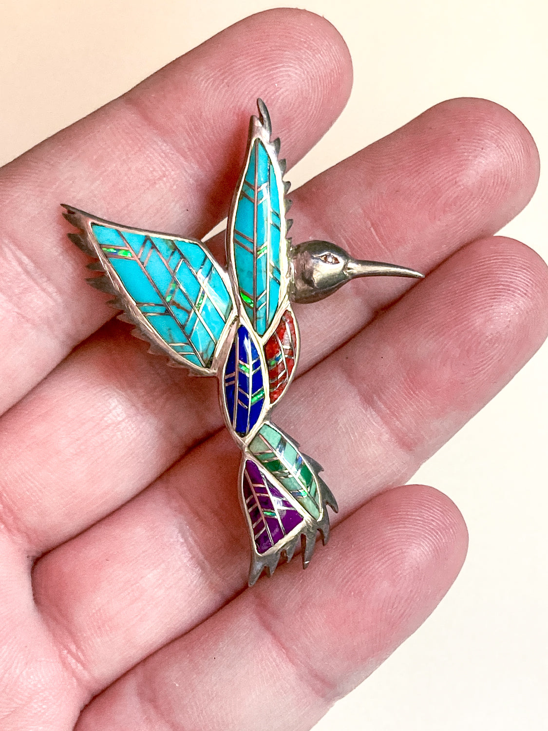 Colorful hummingbird brooch held in a hand against a beige background Vintage Sterling Silver Turquoise Gemstone Mosaic Inlay Hummingbird Brooch